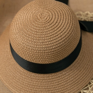 Close-up of woven straw texture and elegant black ribbon detail on a summer sun hat