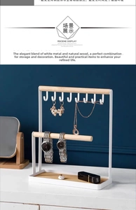 Detail of white iron jewelry stand with 8 hooks and wooden bar for necklace storage