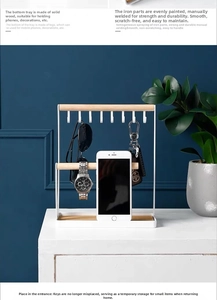 Close-up of minimalist white iron jewelry rack with wooden tray and phone holder base