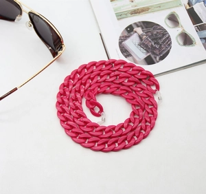 Close-up of rose red acrylic chunky eyewear chain styled with sunglasses on a magazine