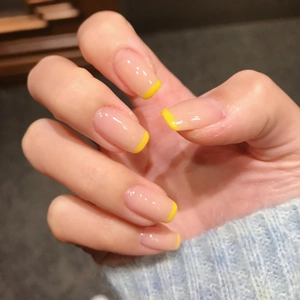 Minimalist nude pink French press-on nails with bright yellow tips on natural hands