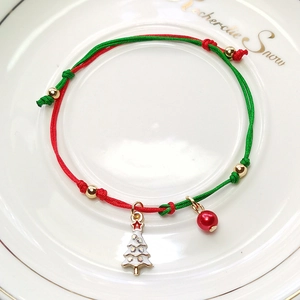 Detail of red and green woven Christmas bracelet with a festive tree pendant and red bead