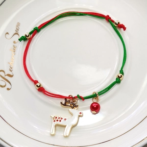 Christmas woven bracelet with red green cords and reindeer enamel charm on white plate