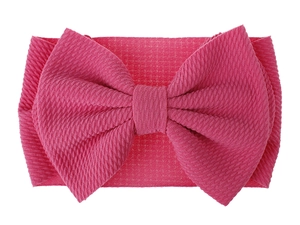 Detailed view of bright pink baby headband featuring a large ribbed knit fabric bow