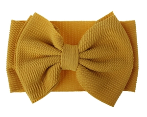 Detailed close-up of yellow oversized bow headband in soft textured knit fabric