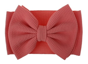 Macro shot of coral pink waffle fabric texture on a large baby bow headband