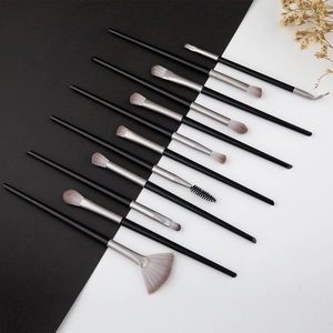 Détail macro de 10 pinceaux maquillage avec poils dégradés et manches noirs laqués