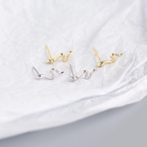 Macro shot of gold and silver S925 sterling silver snake earrings with tiny diamonds