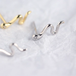 Macro view of silver and gold snake-shaped earrings with sparkling zircon settings
