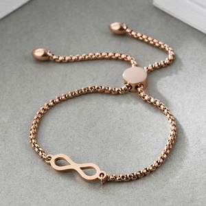 Bracciale infinito in oro rosa con catena a scatola regolabile su sfondo grigio