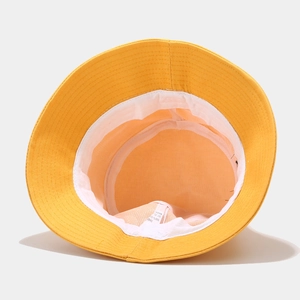 Detailed interior of yellow cotton bucket hat showing white lining and fabric care label