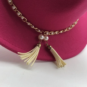 Detail of rose pink wool fedora with gold chain, white pearls and silk tassel accents