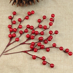 Three vibrant red artificial berry branches on rustic burlap for Christmas home decor