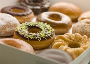 Close-up of assorted glazed donuts with colorful sprinkles in a paper bakery box