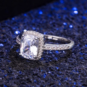 Classic silver ring with square cushion-cut zircon and pave settings on deep blue background