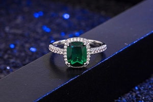 Macro detail of emerald-cut green zircon ring with sparkling pave diamonds and silver band