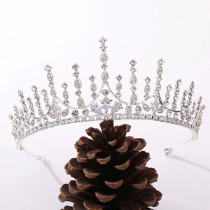 Detailed close-up of a silver bridal tiara with zircon inlay displayed on a pine cone