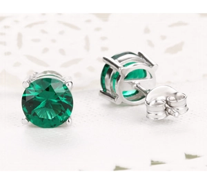 Détail macro de boucles d'oreilles en argent avec pierre précieuse ronde vert émeraude