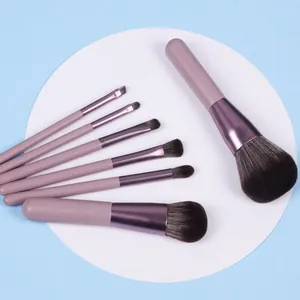 Flat lay of 7 purple professional makeup brushes with soft bristles on a white display