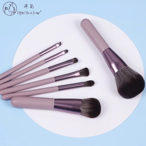 Flat lay of 7 purple professional makeup brushes with soft bristles on a white display