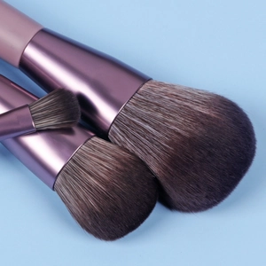 Detail of three purple metal makeup brushes with soft dual-tone bristles and fiber tips