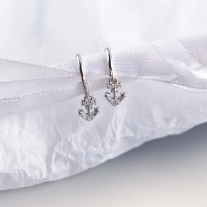 Detailed view of silver S925 anchor hoop earrings with sparkling zircon on white silk