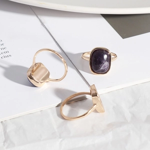 Three gold alloy rings set with rectangular purple natural stones on a white background