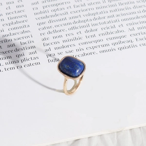 Lapis lazuli rectangular stone ring with gold band on a decorative magazine background