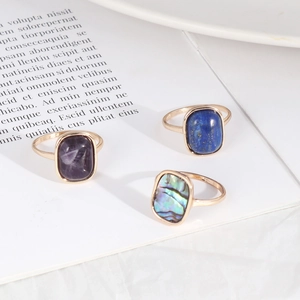 Detailed shot of gold rings featuring rectangular amethyst, lapis, and abalone shell stones