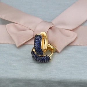 Detailed close-up of golden hoop earrings with micro-paved navy blue zircon stones