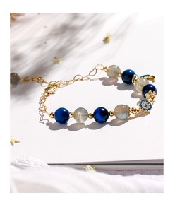 Detail of beaded bracelet with blue kyanite, grey moonstone, and evil eye pendant
