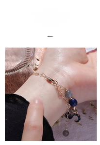 Detailed view of beaded bracelet with heart-shaped links and celestial moon charm