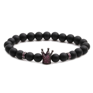 Detailed macro of matte black beads bracelet with bronze crown and pink zircons