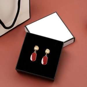 Detailed view of red and gold irregular oval earrings in a black velvet jewelry box