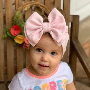 Pink waffle knit baby headband featuring an oversized decorative bow for infants