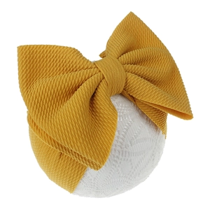 Detailed view of ginger yellow oversized bow headband with soft waffle knit texture