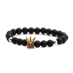 Detail of matte black beads bracelet with a gold crown charm and black zircons