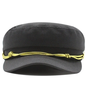 Detail of black military cap featuring gold braided rope and metal side buttons