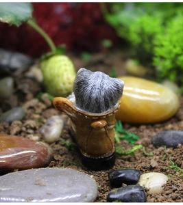 Macro detail of a grey resin kitten figurine sitting inside a brown miniature work boot