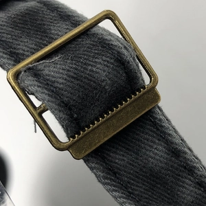 Close-up of adjustable strap with vintage bronze metal buckle on dark gray baseball cap