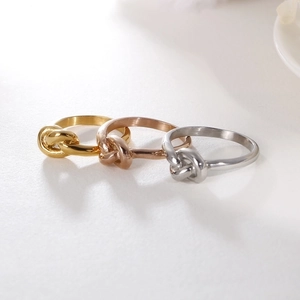 Three minimalist knot rings in gold, rose gold and silver finishes on beige background