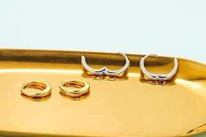 U-shaped glossy hoop earrings in gold and silver finish set on a metal tray
