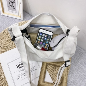 White minimalist canvas messenger bag with large capacity shown with everyday essentials