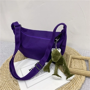 Detail of purple canvas crescent bag with adjustable strap and cute frog plush pendant