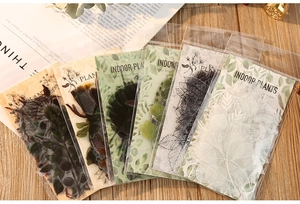 Detailed fan layout of PET indoor plant stickers on a vintage wooden desk with books