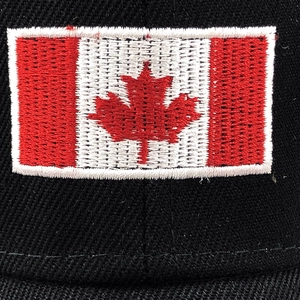 Close-up of Canada flag embroidery on the front of a black baseball cap with fine stitching
