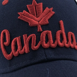 Detail showing 3D embroidered red maple leaf and Canada text on navy cotton cap