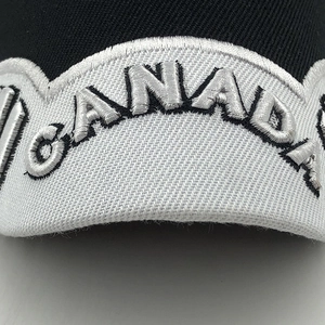 Macro view of white embroidered CANADA lettering on a black cotton baseball cap