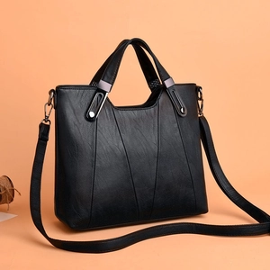 Klassische schwarze PU-Lederhandtasche mit V-Nähten und Doppelgriffen auf orangefarbigen Kontrasten auf Hintergrund