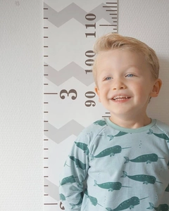Detail showing high-quality wooden height chart with cute narwhal patterned child shirt